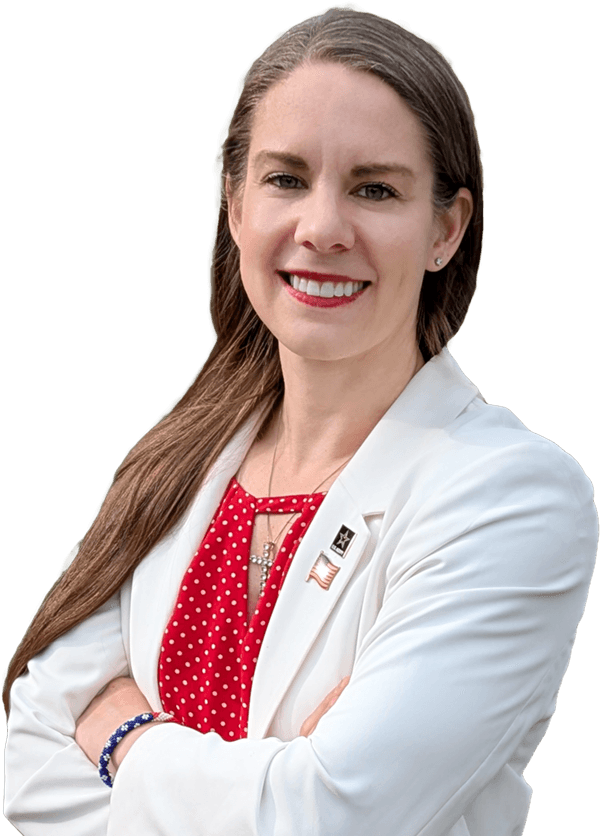 Headshot of Kristy Janigo wearing a white blazer over a red blouse with a cross necklace, army pin, and American flag pin.