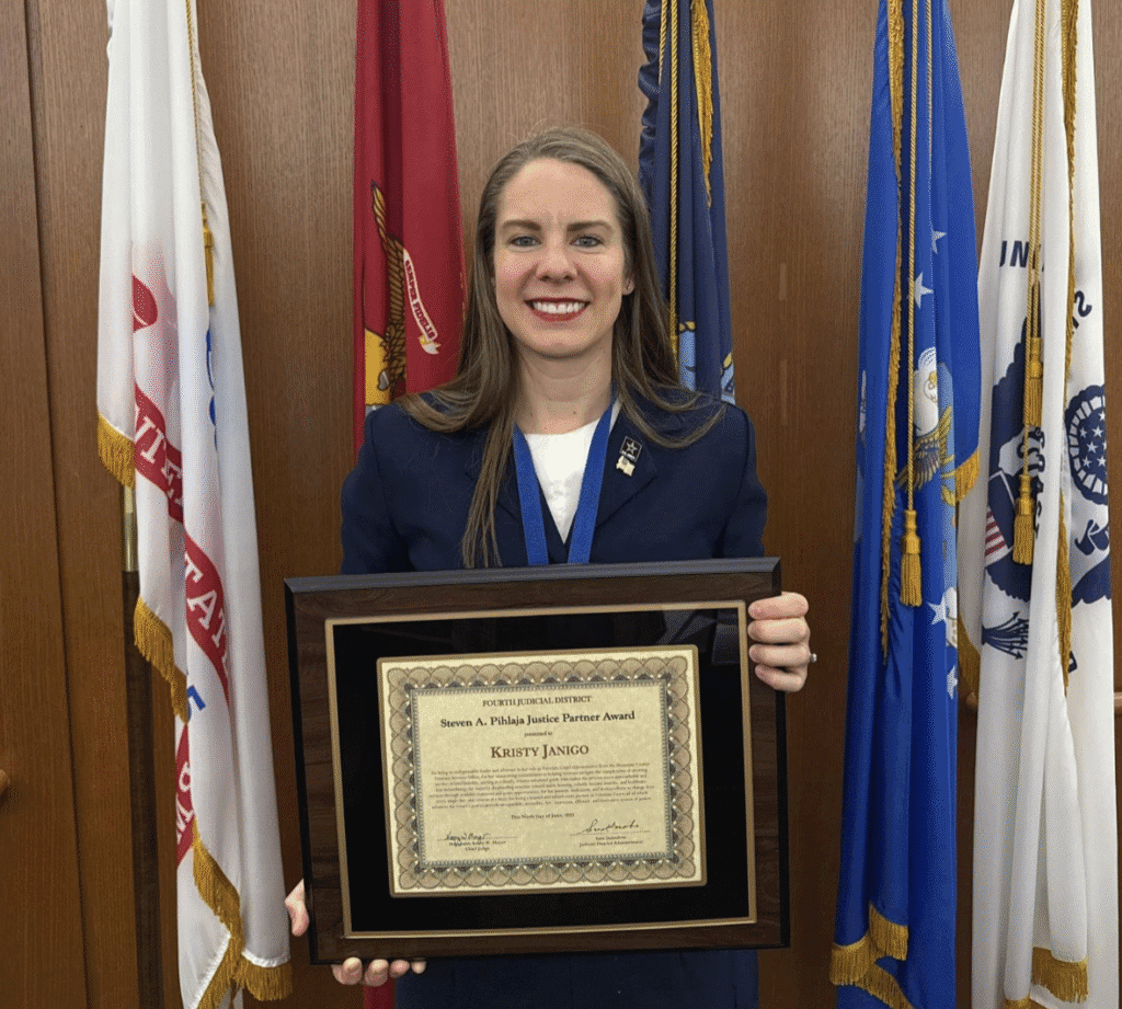 Photo of Kristy standing in front of military flags holding the Steven A. Pihlaja Award