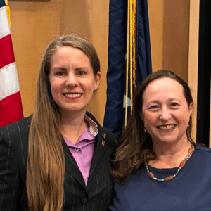 Kristy Janigo and Kristin Bahner standing in front of an American flag and a Minnesota Flag